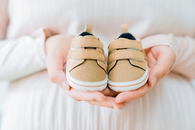 Newborn concept with hands holding shoes