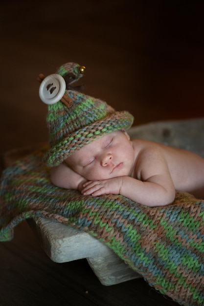 Newborn in gnome hat sleeping in wooden green rug