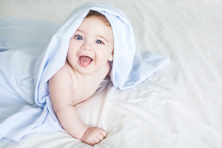  Newborn toddler boy laughing on the bed Premium Photo