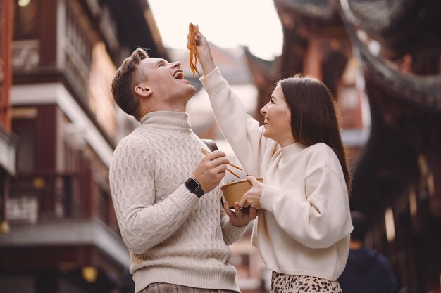 上海の食品市場の外で箸で麺を食べる新婚カップル