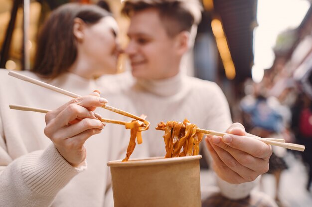 上海の食品市場の外で箸で麺を食べる新婚カップル