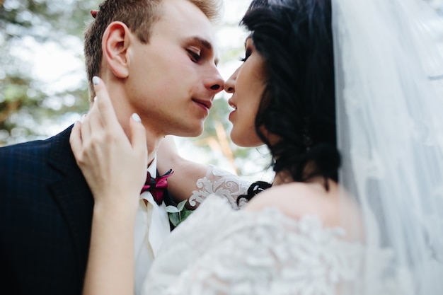 Newlyweds embracing touching noses standing outside
