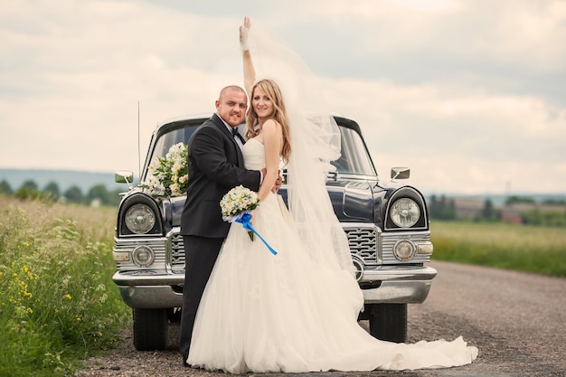 Newlyweds in front of a car