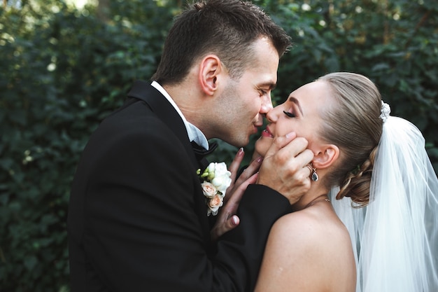 Newlyweds kissing in forest