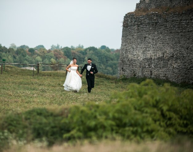 Newlyweds running through a green field