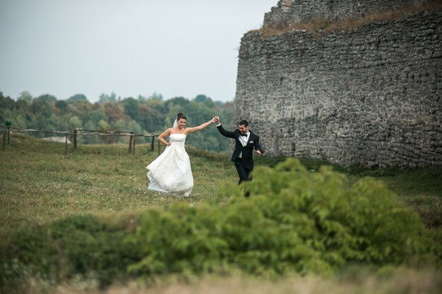 Newlyweds running through a green field