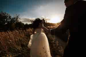 Free photo newlyweds walking at sunset in the field