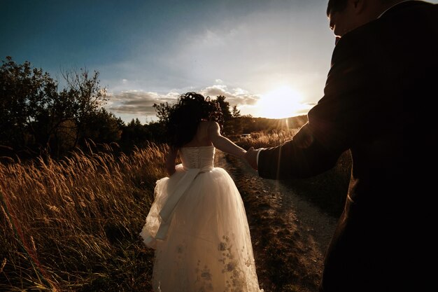 Newlyweds walking at sunset in the field