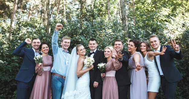 Free photo newlyweds with friends posing in park