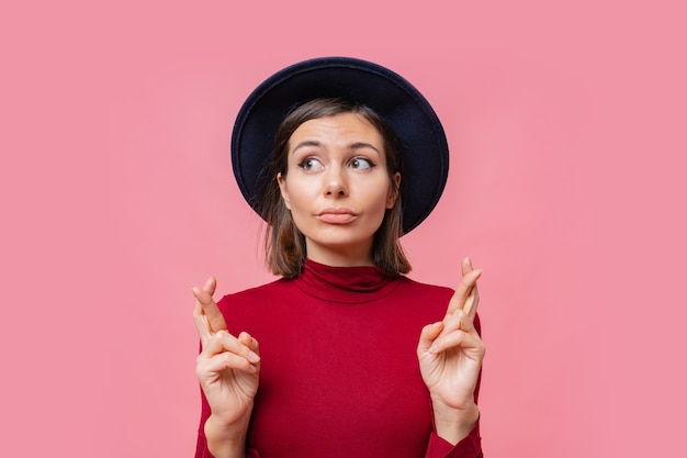 Free photo nice cheerful woman wishes to do her best to keep her fingers crossed, has the best, wearing in red jamper isolated