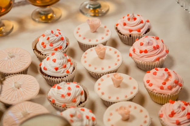 Nice cupcakes with rose sugar and white glaze stand on the white