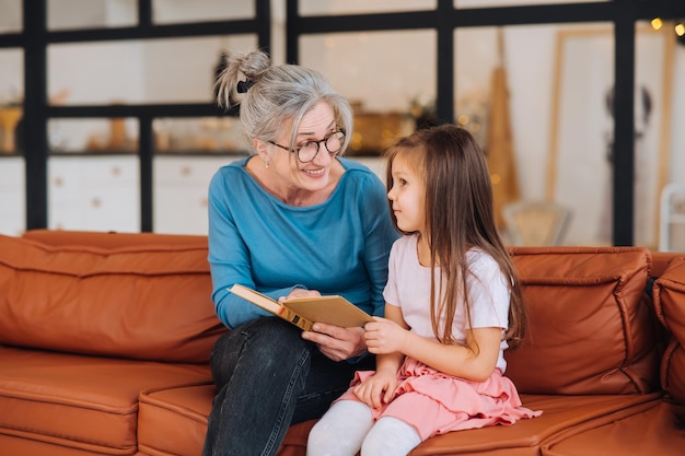 Nice elderly woman grandmother reading story to granddaughter