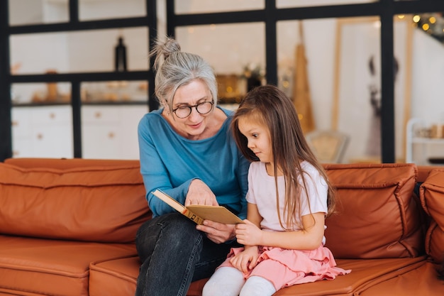 Nice elderly woman grandmother reading story to granddaughter