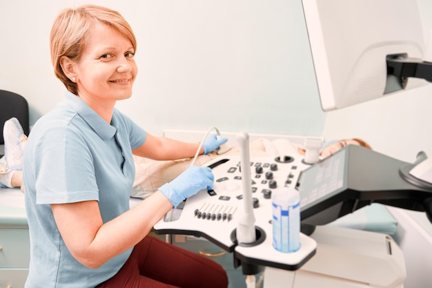 Nice female doctor performing ultrasound procedure in clinic