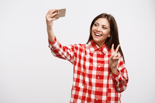 Nice girl in fashion check shirt taking selfies with smile