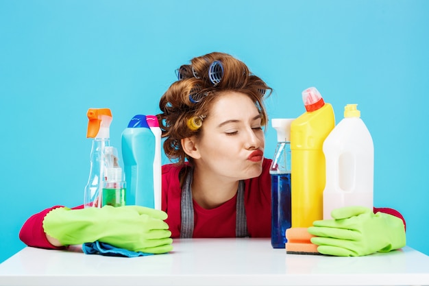 Nice girl sits on behind table and cleaning tools holding them