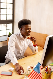 仕事​で​食事​を​し​ながら​コンピューター​の​前​に​座っている​素敵な​勤勉な​男