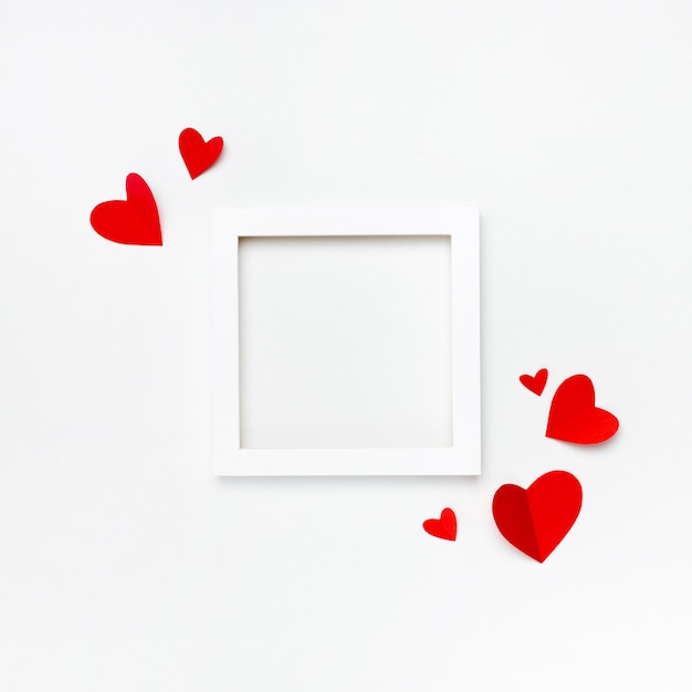 Nice square white frame with copyspace for text on white background decorated with handmade paper hearts