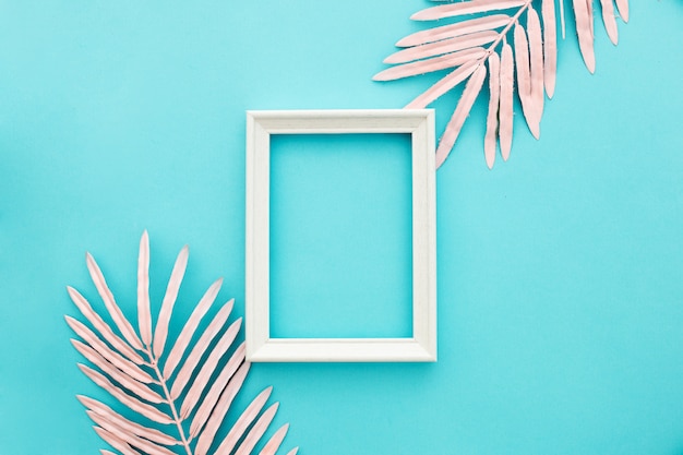 Nice white frame on blue background with pink palm leaves