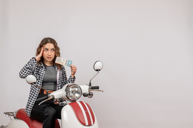 nice young girl on moped holding ticket on grey