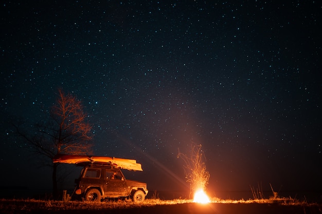 明るいキャンプファイヤーと車のある夜の風景