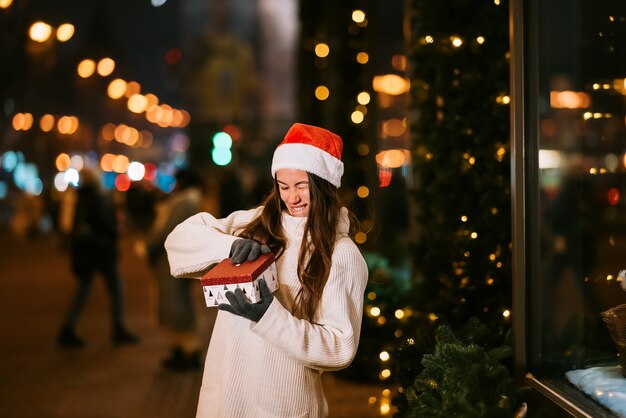 Night street portrait of young beautiful woman acting thrilled. Festive garland lights.