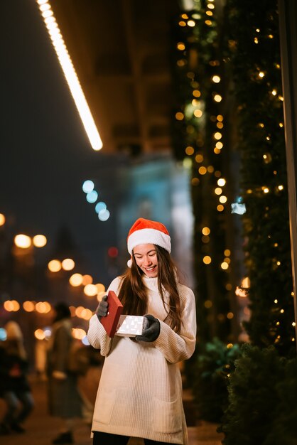 Night street portrait of young beautiful woman acting thrilled. Festive garland lights.