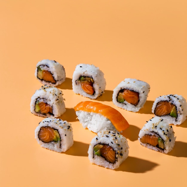 Nigiri sushi with maki rolls on yellow background