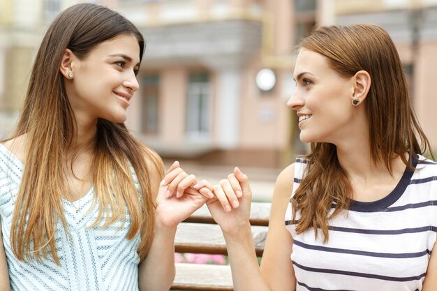 No more fighting Portrait of two best friends making hands promise sitting together on a bench in the city