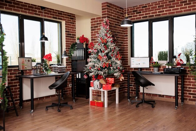 No people in empty business office with festive decor, christmas tree and seasonal holiday ornaments to celebrate winter tradition in corporate startup workplace. Xmas season decorations.