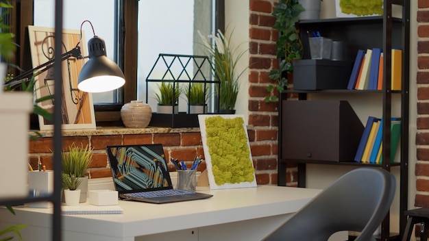 No people at empty desk with laptop computer in apartment, to use modern digital technology for entertainment. Nobody at home office with interior decorations, creative indoors style.