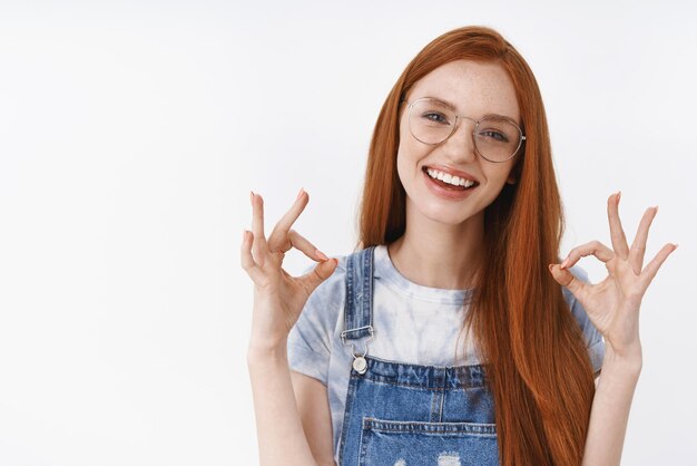 No problem everything ok Cheerful optimistic redhead european girl wear glasses show okay approval sign smiling pleased recommend good quality product satisfied service stand white background