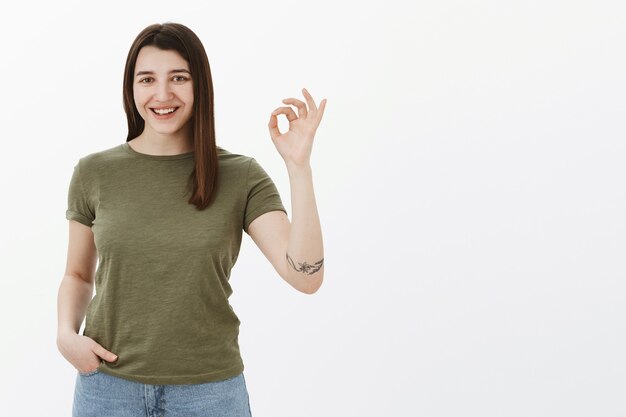 No problem, it deal. Ambitious and confident good-looking delighted young female student showing okay sign and smiling satisfied as agree, liking and recommending product over gray wall