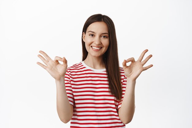 No problem. Satisfied young woman shows okay zero, OK sign and nod in approval, praise good choice, compliment you, agree and like something good, white background.