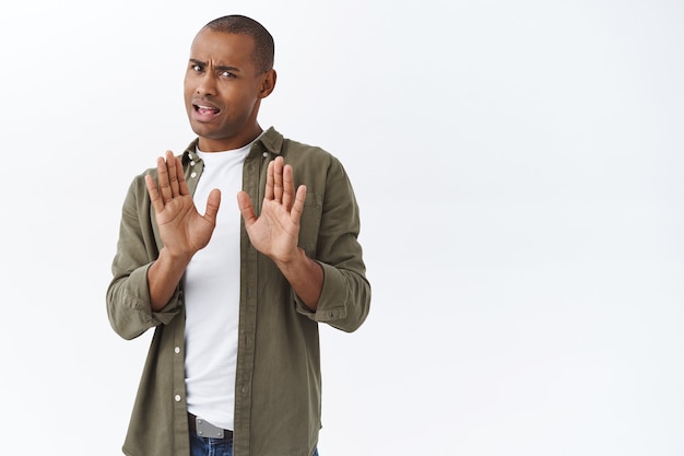 Free photo no thank you, i pass. portrait of young african-american man rejecting persons offer, raising hand in block