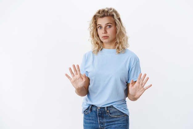 No thanks. Alarmed and intense young attractive woman with short curly hair holding palms near chest in refusal and rejection gesture looking reluctant, unwilling and declining proposal