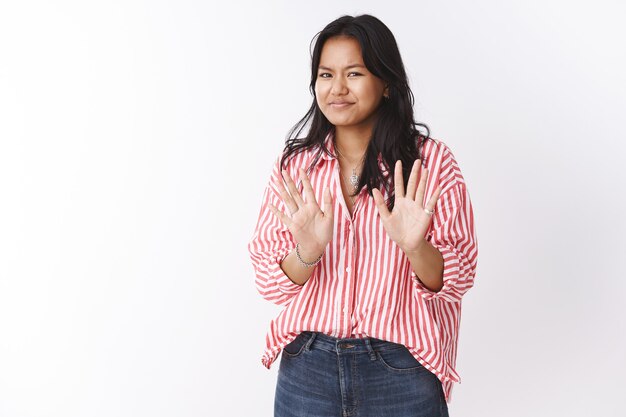 No thanks I fine. Portrait of awkward woman saying sorry refusing offer, waving palms near chest reluctant, smirking and shaking head in negative response, posing against white wall