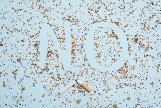 No word made with tobacco and broken cigarette against blue background