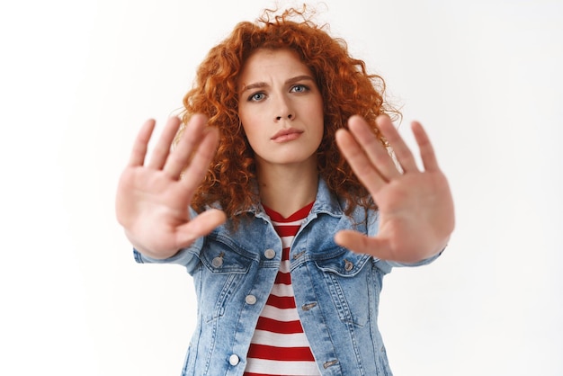 Free photo no you must stop seriouslooking displeased ginger girl 25s curly hairstyle extend palms forward frowning prohibiting asking hold on give restriction demanding forbid bad treatment animals