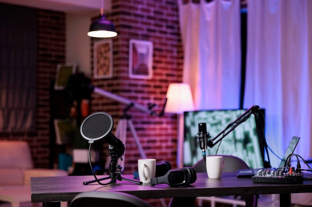 Nobody at empty desk with streaming equipment to broadcast live conversation on social media. No people in space with podcast station, microphone and headphones, sound production.