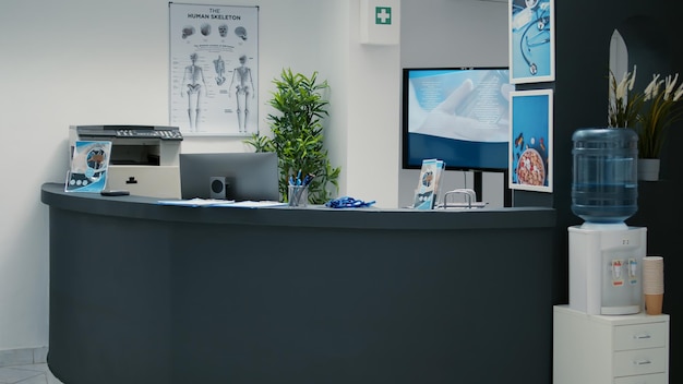 Nobody in empty waiting room lobby with desktop at reception, helping patients with medical insurance to attend checkup visit appointment. Waiting area with counter at hospital.