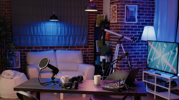 Nobody in podcast production studio with professional microphone and headphones for streaming interview on internet radio. Empty desk with streaming equipment to broadcast live show on social media.