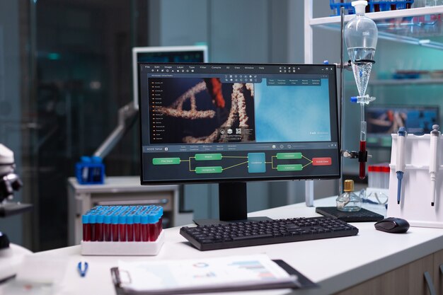 Nobody in scientific laboratory with research equipment at clinic. Empty microbiology cabinet for medical development designed with modern technology and blood vacutainers on desk