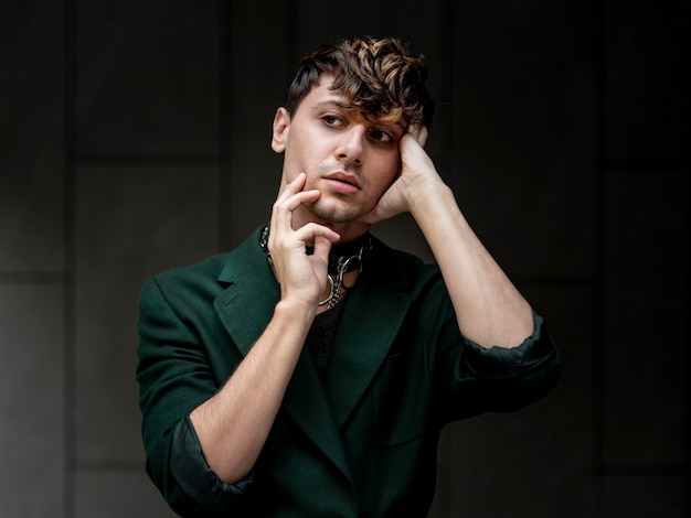 Non binary person in green jacket posing on a dark alley