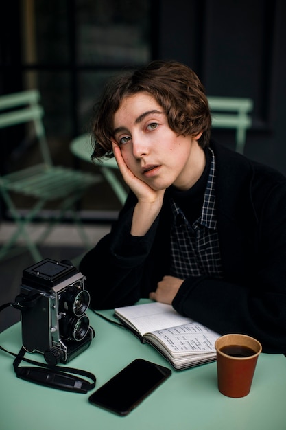 Free photo non binary person sitting at a table in retro clothes