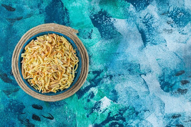 Noodle in a bowl on a trivet , on the blue table. 