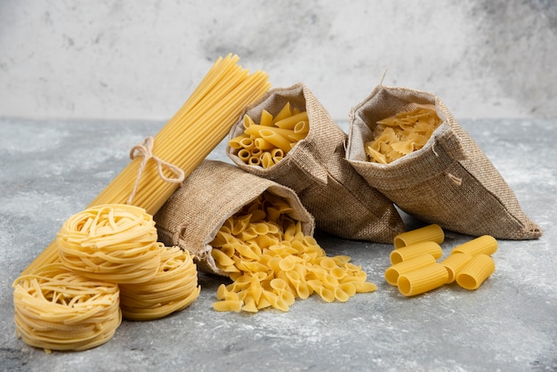 Free photo noodle and pasta varieties in rustic baskets and marble table.