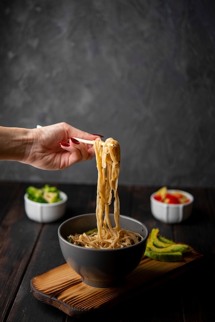 Noodles in bowl with avocado and copy space