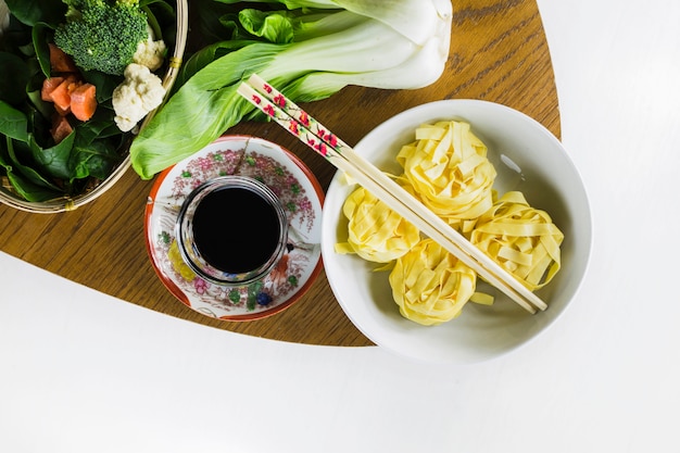 Noodles near soy sauce and vegetables