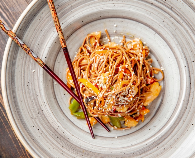 Noodles prepared with chicken peppers sesame seeds and sauce